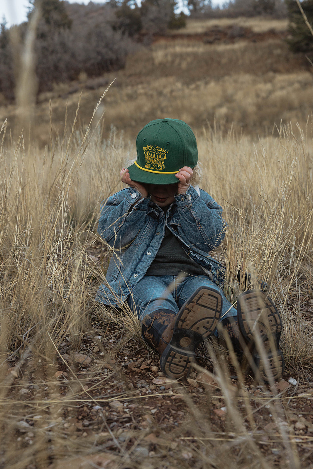 Toddler wearing snapback hat while playing outside in natural light. 