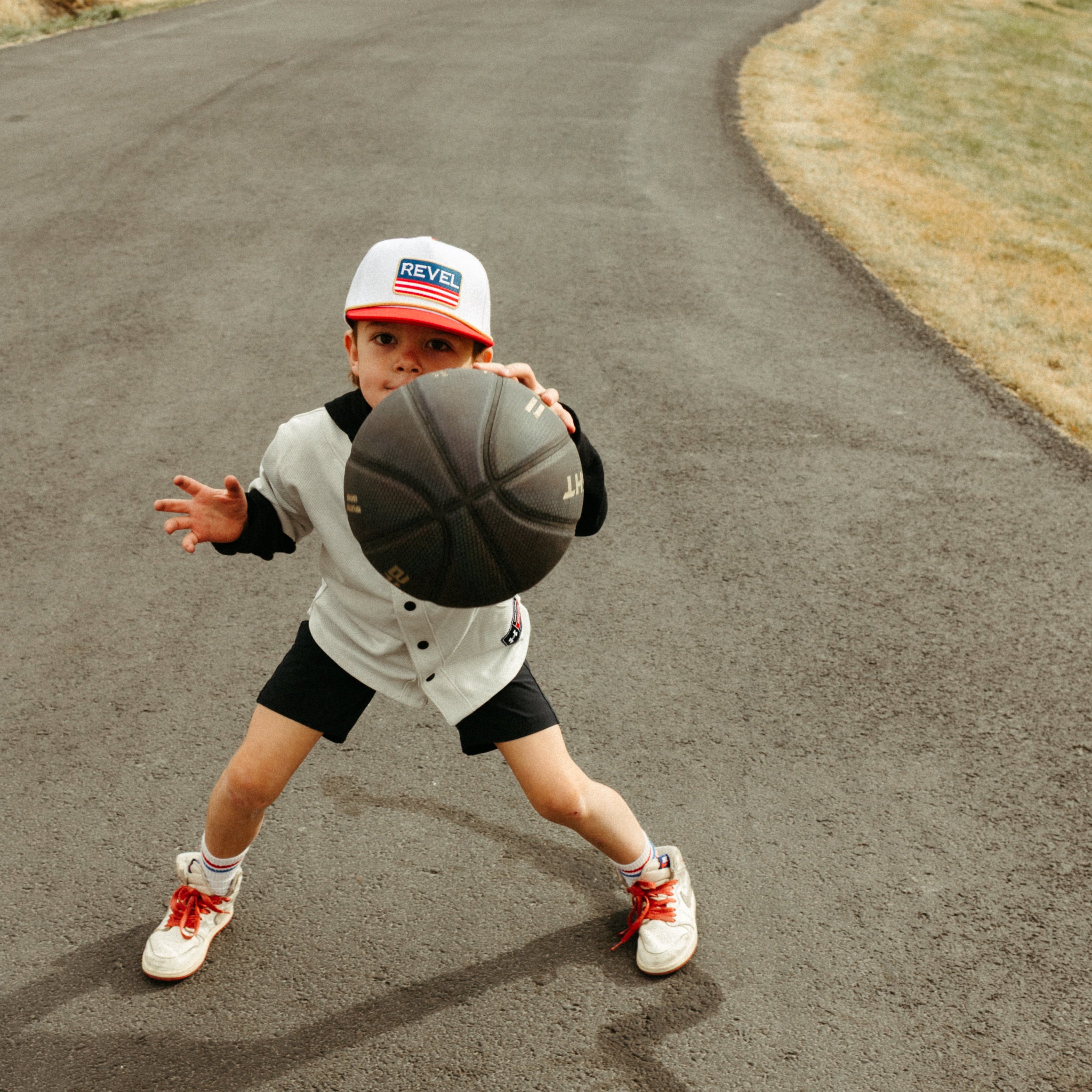 Child playing basketball wearing a red American snapback hat